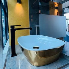 Ein elegantes, freistehendes Waschbecken mit goldener Unterseite und schwarzem Wasserhahn in einem modernen Badezimmer.