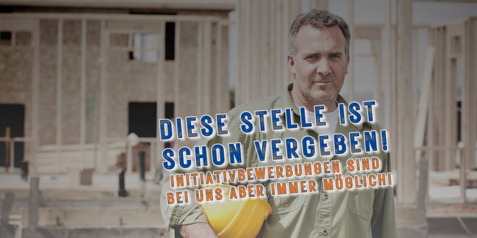 Ein Bauarbeiter steht mit einem gelben Helm in einem Rohbau und schaut direkt in die Kamera, während er ernst wirkt.
