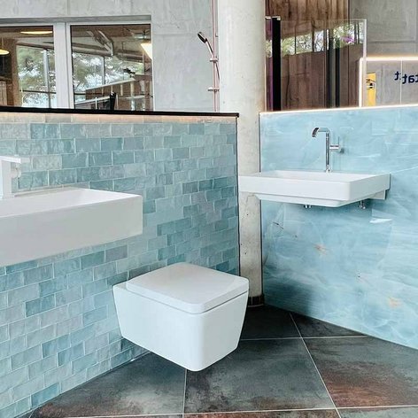 Ein modernes Badezimmer mit einer eleganten Wand aus blauen Fliesen und einem schwebenden Waschbecken.