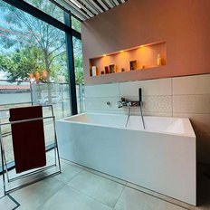 Ein modernes Badezimmer mit einer eleganten weißen Badewanne und einem Handtuchhalter, der ein rotes Handtuch zeigt.