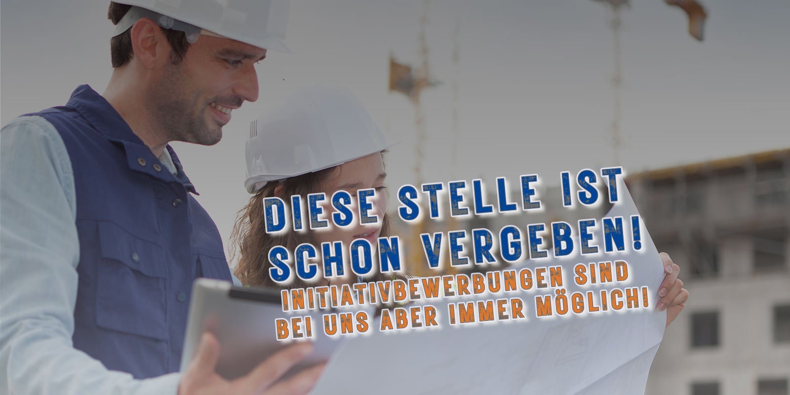 Ein Mann und eine Frau betrachten gemeinsam einen Bauplan auf einer Baustelle, beide tragen Sicherheitshelme.